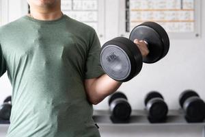 uomo allenarsi nel il interno palestra, uomo sollevamento su un' martello arricciare peso esercizio. bodybuilding manubri nel palestra. formazione nel fitness palestra. foto