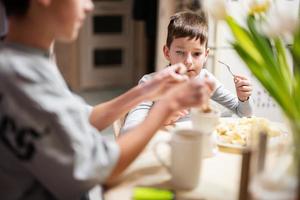 bambini mangiare frutta e dolci, bevanda tè a casa nel il sera cucina. cioccolato su un' bastone per fusione. foto