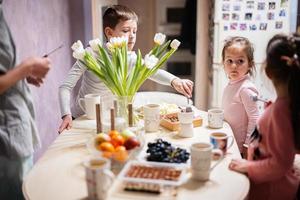 bambini mangiare frutta e dolci, bevanda tè a casa nel il sera cucina. foto