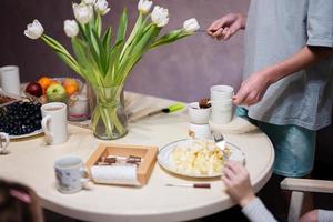 bambini mangiare frutta e dolci, bevanda tè a casa nel il sera cucina. cioccolato su un' bastone per fusione. foto