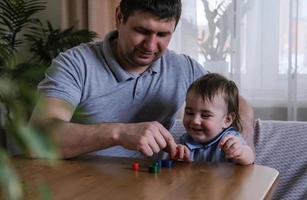 papà e 1 anno figlio giocare con di legno figurine a casa. sviluppo di bene il motore abilità e logico pensiero di bambini. Il padre di giorno concetto foto