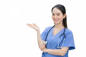 professionale asiatico bellissimo giovane donna medico in piedi sorridente con fiducia nel un' blu uniforme mentre lei Spettacoli sua mano per presente qualcosa isolato su bianca sfondo. foto