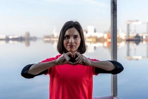 carino giovane donna mostrando cuore cartello con mani su un' barca foto