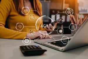 agile sviluppo metodologia concetto. attività commerciale mano utilizzando il computer portatile e tavoletta con virtuale schermo agile icona su moderno ufficio digitale tecnologia concetto. foto