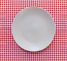 piatto bianco su panno a scacchi rosso foto