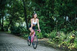 giovane donna in sella a una bicicletta nel parco foto