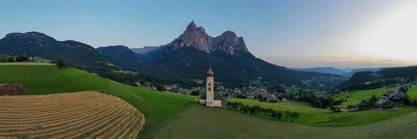 st. valentin castelrotto villaggio Chiesa nel il estate nel il dolomite Alpi. sorprendente paesaggio con piccolo cappella su soleggiato prato e petz picco a castelrotto comune. dolomiti, Sud tirolo, Italia foto