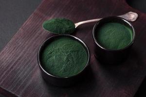 Spezia, verde colore spirulina nel il modulo di polvere nel un' nero ciotola foto