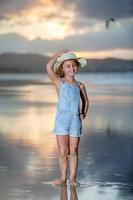 allegro ragazza su bagnato spiaggia a tramonto foto