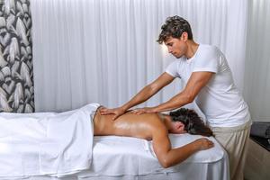 professionale massaggiatore l'esecuzione un' corpo massaggio per rilassato donna dire bugie viso giù su massaggio tavolo foto