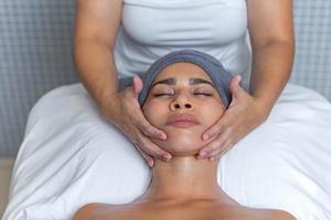 estetista dando un' facciale massaggio con crema su un' rilassato donna di viso a Salute terme foto