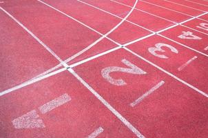 numeri di partenza punto su rosso in esecuzione pista, corsa traccia e verde erba, diretta Atletica in esecuzione traccia a sport stadio foto