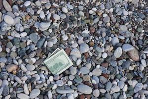 centinaio dollari metà coperto con il giro rocce menzogna su spiaggia foto