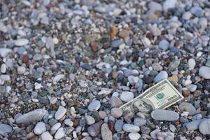 centinaio dollari metà coperto con il giro rocce menzogna su spiaggia foto