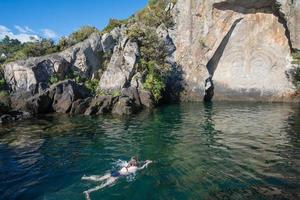 turista nuoto nel grande lago tortora con maori roccia intagli il iconico turista attrazione posto nel lago tortora, nuovo zelanda. foto