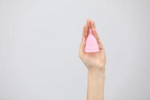 vicino su di donna mani Tenere mestruale tazza isolato su bianca. eco-friendly concetto per Da donna Salute, mestruazioni. innovazione Prodotto nel ginecologia foto