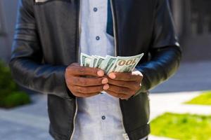 avvicinamento foto di il mano di un africano americano uomo d'affari conteggio denaro contante dollari