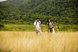 coppia sorridente che cammina con zaini su verdi colline
