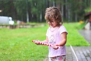 adorabile ragazza a piedi con giocattolo a piovoso giorno foto