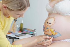 trucco artista disegnare un' piccolo bambino piccolo su il pancia foto