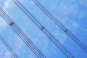 alta tensione e isolato cavi sospeso nel il blu cielo siamo cavi quello trasportare elettricità e elettricità per persone e molti industriale impianti e aziende quello bisogno elettricità. foto