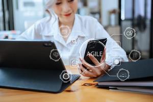 agile sviluppo metodologia concetto. attività commerciale mano utilizzando il computer portatile computer e tavoletta con virtuale schermo agile icona su moderno ufficio digitale tecnologia concetto. foto