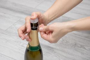 femmina mani Aperto un' bottiglia di Champagne foto