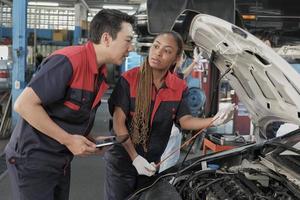 maschio professionale settore automobilistico supervisore consiglia e ispeziona nero femmina meccanico lavoratore di liquido motore olio a auto box auto, servizio Manutenzione, e fissaggio specialista occupazioni auto industria. foto