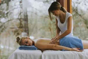 bella giovane donna sdraiata e con massaggio alla schiena nel salone spa durante la stagione invernale