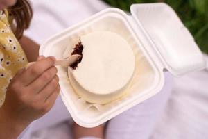 un Aperto bianca scatola ecologica con un' di legno cucchiaio e un' cioccolato bento torta nel il mani di un' persona foto