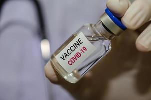 un dottore maschio con in mano una bottiglia del vaccino covid-19 o del coronavirus