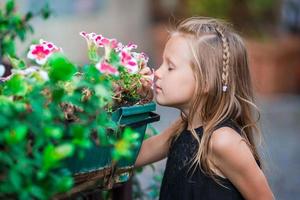 bellissimo poco ragazza annusando fiori foto