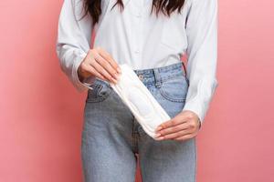 studio tiro di un' giovane ragazza con mestruale imbottitura nel sua mani. il concetto di femminile igiene. foto