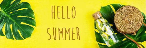 Ciao estate bandiera per sito web. il giro malacca Borsa e bicchiere bottiglia con limonata e Monstera foglia foto