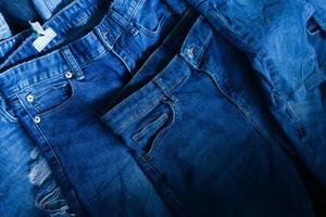 pila di vario occhiali da sole blu jeans. mucchio blu denim jeans struttura striscione. tela denim moda struttura foto