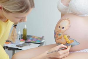 trucco artista disegnare un' bambino piccolo su il pancia foto