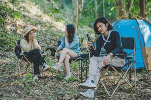 giovane donne seduta e bevanda bevanda davanti di campeggio tenda foto