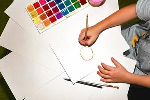 avvicinamento di figli di mani disegno con un' matita su bianca carta. nel il processi di opera. foto