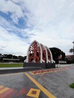 mataram, Indonesia, febbraio 16, 2023. un' cancello con il forma di un' bianca tradizionale Casa tetto e un' rosso stoffa motivo nel sangkaraang parco nel il centro di mataram città foto