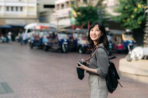 giovane asiatico donna zaino viaggiatore utilizzando digitale compatto telecamera, godendo strada culturale Locale posto e Sorridi. viaggiatore controllo su lato strade. foto