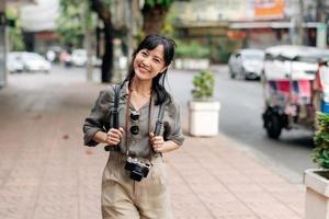 giovane asiatico donna zaino viaggiatore godendo strada culturale Locale posto e Sorridi. viaggiatore controllo su lato strade. foto