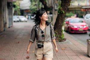 giovane asiatico donna zaino viaggiatore godendo strada culturale Locale posto e Sorridi. viaggiatore controllo su lato strade. foto