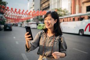 giovane asiatico donna zaino viaggiatore godendo Cina cittadina strada cibo mercato nel bangkok, Tailandia. viaggiatore controllo su lato strade. foto