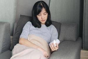 asiatico donna con freddo e influenza lettura Istruzioni su medicina bottiglia foto