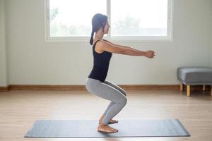 lato Visualizza di un' donna in piedi con braccia esteso per tutti e due lati e ginocchia leggermente minore. preparare per yoga nel il camera. foto