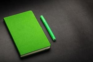 verde bloc notes con un' pennarello penna su un' nero sfondo, superiore Visualizza. foto