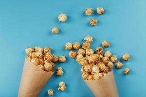 caramello Popcorn nel un' carta Busta su un' blu sfondo. foto