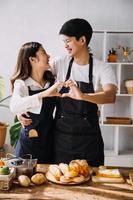 nel cucina perfettamente contento coppia preparazione salutare cibo, molte di verdure. uomo si destreggia con frutta, fa sua fidanzata ridere. bello persone nel amore avere divertimento foto