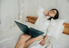 ritratto di stanco bellissimo donna avendo collo dolore a casa dopo Lavorando con il computer portatile computer per un' lungo volta. utilizzando taccuino e serio. pensiero di modo per completare. Salute tecnologia concetto. foto