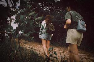 Due giovane asiatico Da donna escursionisti con zaino a piedi su il montagna. Due ragazze a piedi nel natura. a piedi mentre guardare il paesaggio nel il foresta. al di sopra di naturale sfondo. indietro Visualizza. foto